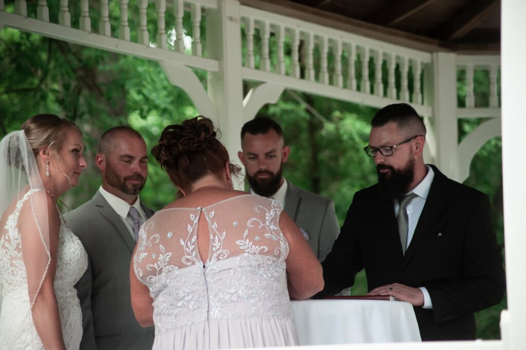 Bride, groom, maid of honor and officiant all sign the marriage certificate.