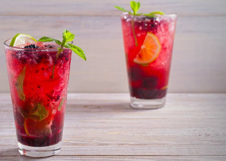 Two berry mojitos on a neutral background.
