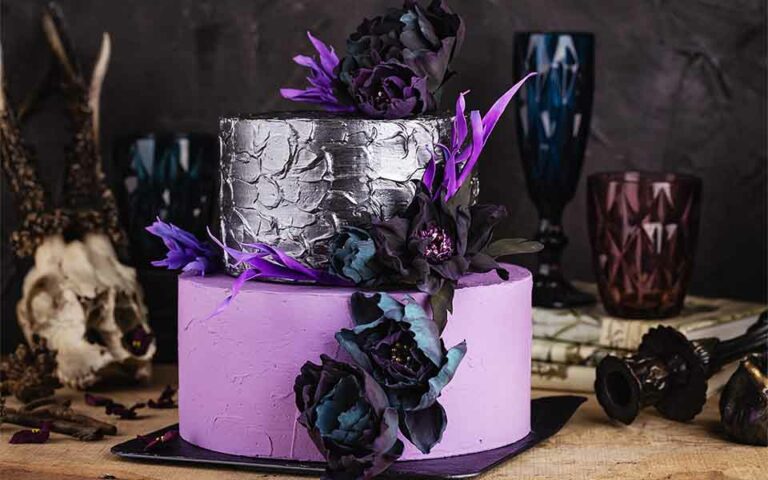 Purple and silver two tiered wedding cake with black and purple flowers.