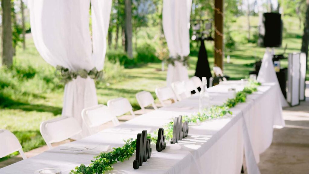White linen covered head table at an outdoor wedding reception.